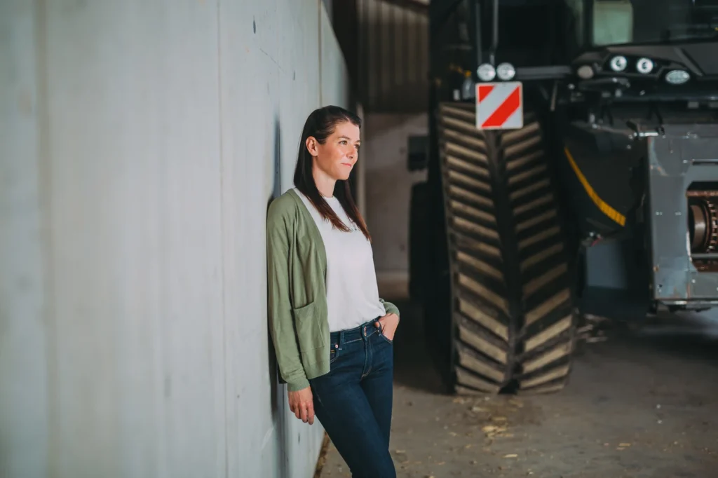 Nina Siebinger steht neben einem Traktor auf ihrem landwirtschaftlichen Betrieb